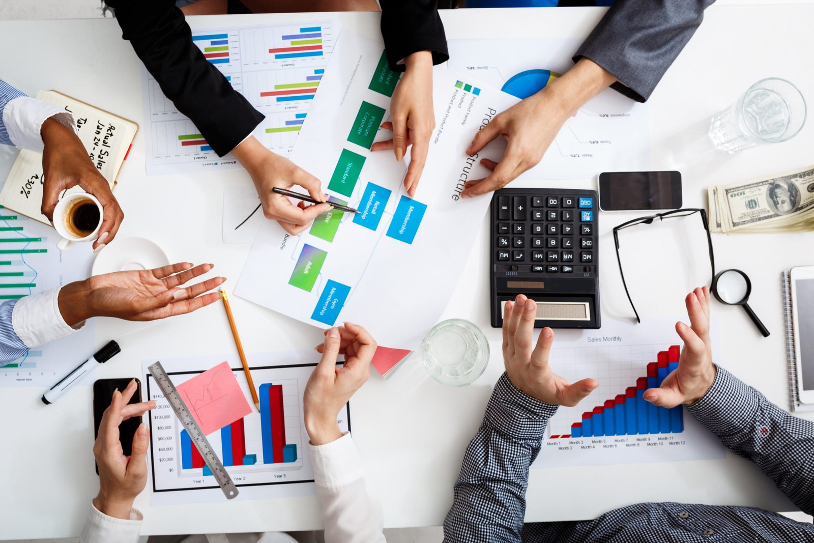 Picture of businessmen's hands on white table with documents, coffee and drafts